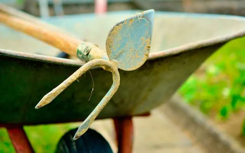Gartenpflege mit Schubkarre und Hacke