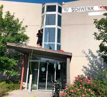 Gebäudereiniger reinigt Glasfassade mit Reinwasser