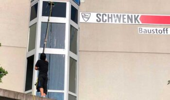 Gebäudereiniger reinigt Glasfassade mit Teleskopstange