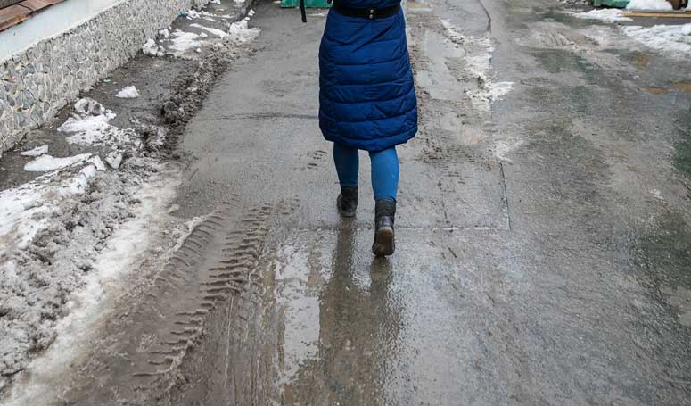 Frau, die durch Schneematsch läuft