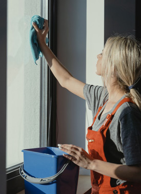 Gebäudereinigung - Mitarbeiterin beim Fensterputzen